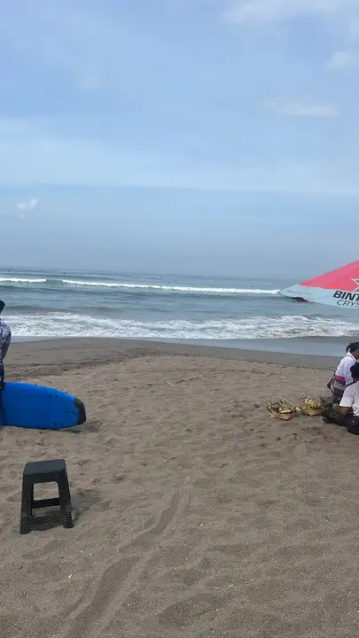 Offerings set out on the sand while surfers wait for the waves.