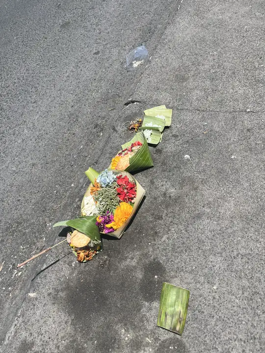 Fresh offerings at the edge of a street, with a stick of incense tucked in.
